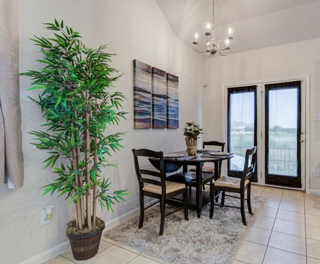 Dining area with a chandelier, light tile patterned flooring, lofted ceiling, and baseboards | Image 4