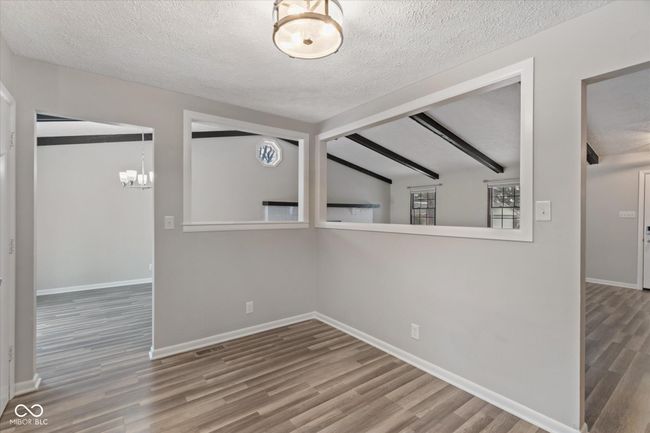 empty room featuring wood finished floors, a textured ceiling, and a chandelier | Image 6