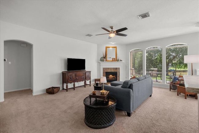 Bright, open-concept living area with a cozy fireplace and large windows while connecting seamlessly to the kitchen with a breakfast bar. | Image 6