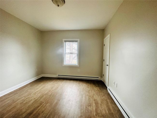 Unfurnished room featuring hardwood / wood-style floors and a baseboard heating unit | Image 5