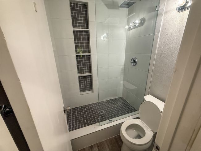 Bathroom with tiled shower, a textured wall, and wood finished floors | Image 20