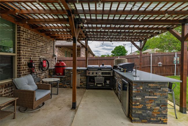 Fenced backyard with extended covered patio and large outdoor kitchen space | Image 16