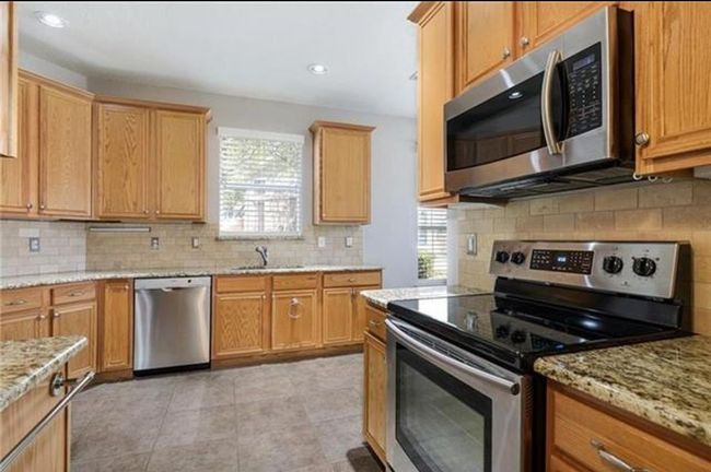 Kitchen featuring appliances with stainless steel finishes, light stone countertops, tasteful backsplash, and light tile floors | Image 5
