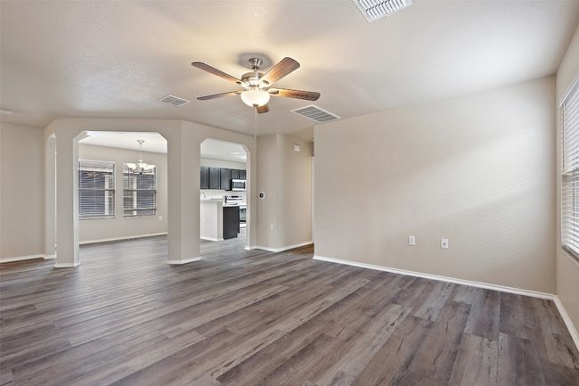Unfurnished living room featuring a chandelier, arched walkways, a ceiling fan, and dark wood-type flooring | Image 7