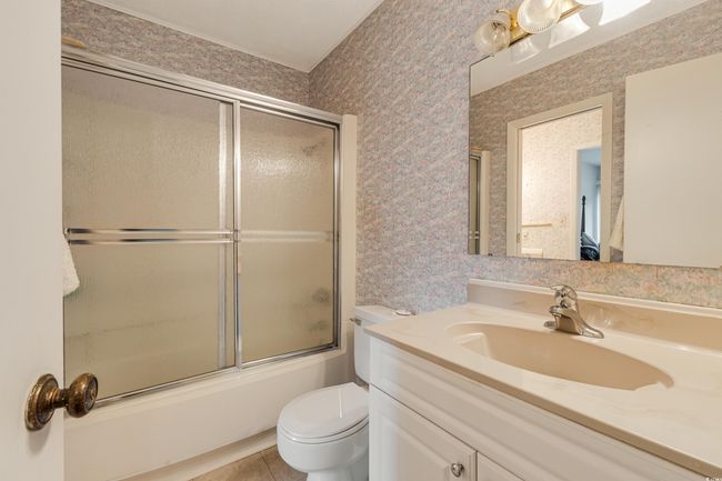 Bathroom featuring wallpapered walls, toilet, vanity, and enclosed tub / shower combo | Image 21