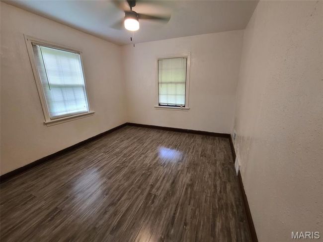 Empty room featuring healthy amount of natural light, wood finished floors, and a ceiling fan | Image 10