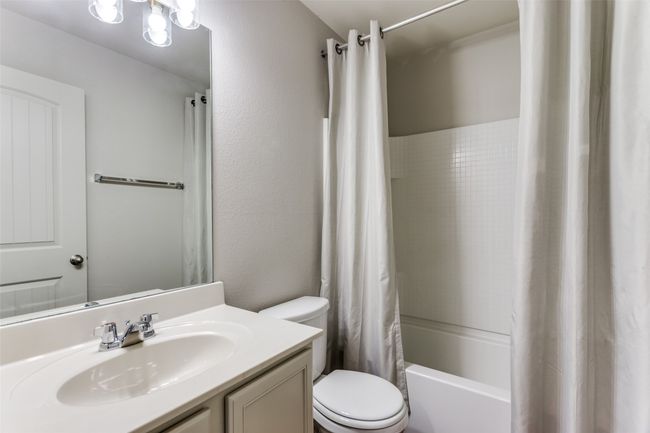 Full bath with vanity, shower / bathtub combination with curtain, and a textured wall | Image 38