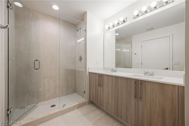 Bathroom with tile patterned floors, a sink, double vanity, and a stall shower | Image 23