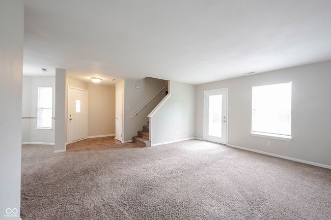 unfurnished living room featuring carpet, visible vents, baseboards, and stairway | Image 7