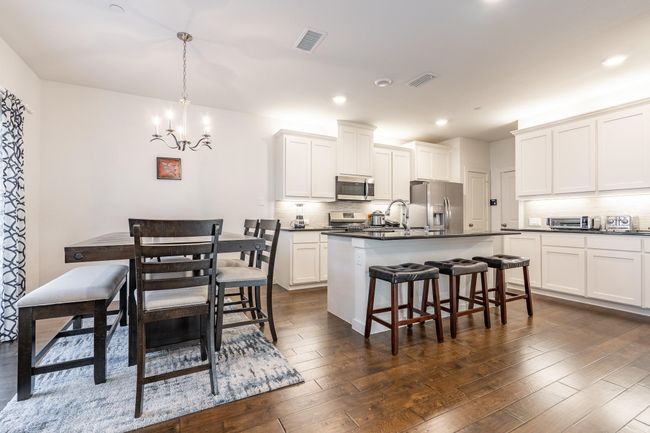 Kitchen featuring visible vents, a chandelier, appliances with stainless steel finishes, dark countertops, and decorative backsplash | Image 6