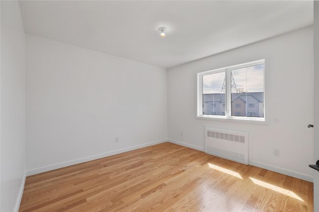 Empty room with radiator heating unit, baseboards, and light wood-style flooring | Image 32