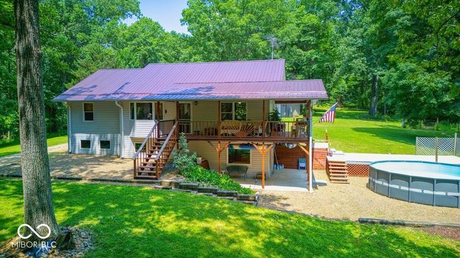 back of house featuring stairway, a yard, a metal roof, an outdoor pool, and a deck | Image 14