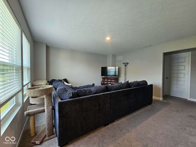 living room with carpet flooring, a textured ceiling, and baseboards | Image 11