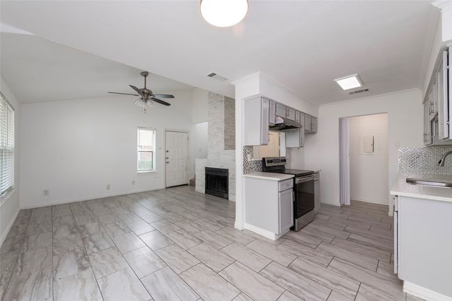 Kitchen featuring electric stove, visible vents, a sink, and open floor plan | Image 7