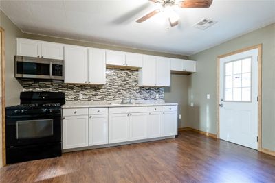 Kitchen featuring white cabinets, sink, tasteful backsplash, black range with gas stovetop, and dark hardwood / wood-style flooring | Image 3