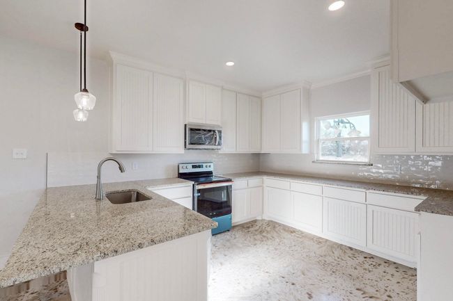 Kitchen featuring stainless steel appliances, a peninsula, a sink, and light stone counters | Image 12