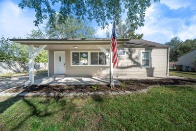 Ranch-style house featuring covered porch and a front lawn | Image 1