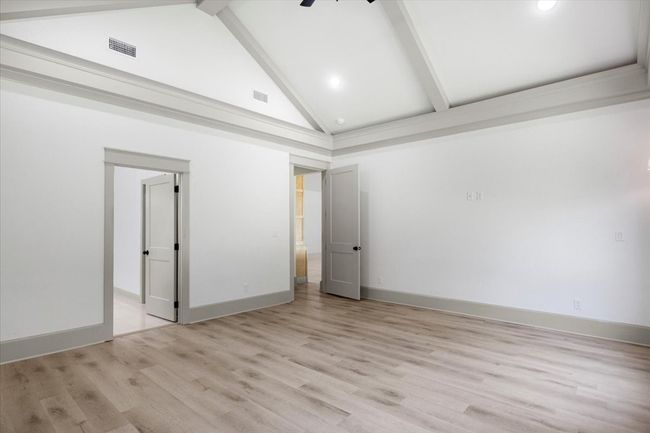 Unfurnished bedroom with high vaulted ceiling, beamed ceiling, and light wood-style flooring | Image 17