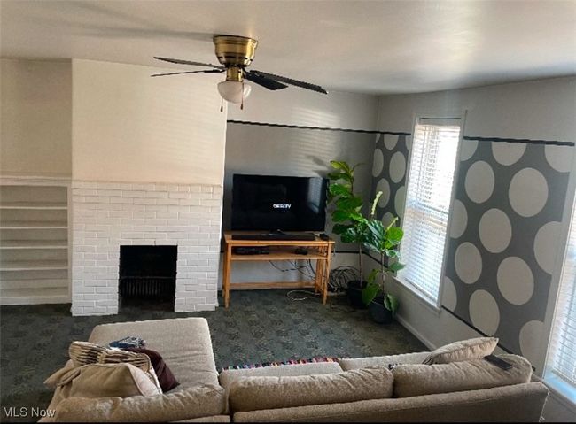 Living room featuring a fireplace, dark carpet, and ceiling fan | Image 11