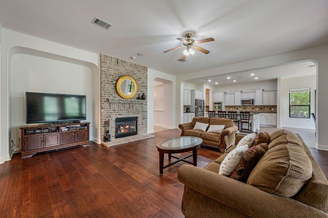 Living room with visible vents, arched walkways, ceiling fan, and dark wood-type flooring | Image 7