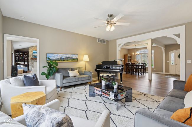 living room with arched walkways, visible vents, ceiling fan with notable chandelier, and wood finished floors | Image 13