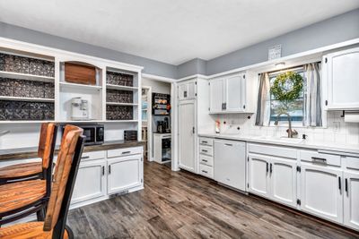 Kitchen with dishwasher, sink, dark hardwood / wood-style floors, decorative backsplash, and white cabinetry | Image 3