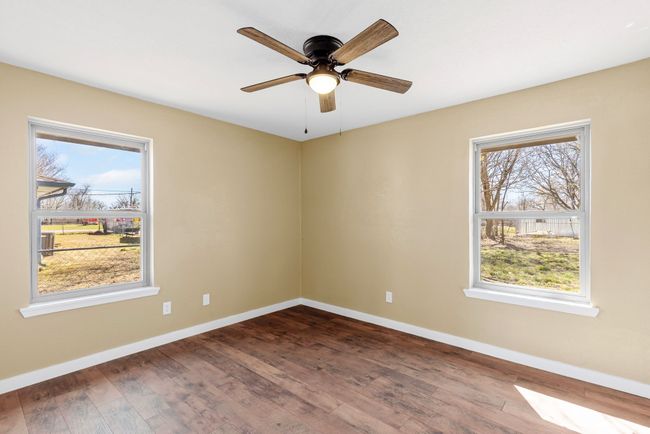 Unfurnished room featuring dark wood-style floors, plenty of natural light, baseboards, and a ceiling fan | Image 22