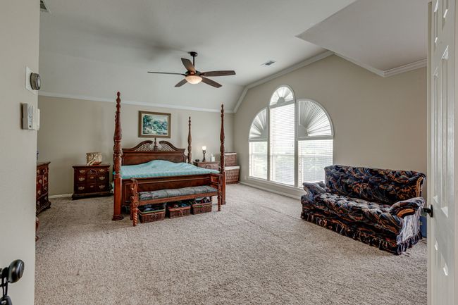 Carpeted bedroom with lofted ceiling, crown molding, and ceiling fan, reading area. Addition space is located to the right of the loveseat. | Image 23