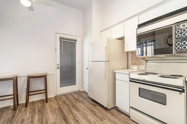 Kitchen with white appliances, white cabinetry, light wood finished floors, light countertops, and ceiling fan | Image 6