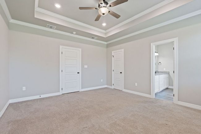 Unfurnished bedroom with light carpet, crown molding, a raised ceiling, ensuite bath, and recessed lighting | Image 17
