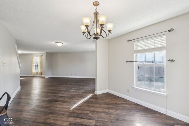 spare room featuring wood finished floors, a chandelier, baseboards, and a textured ceiling | Image 22