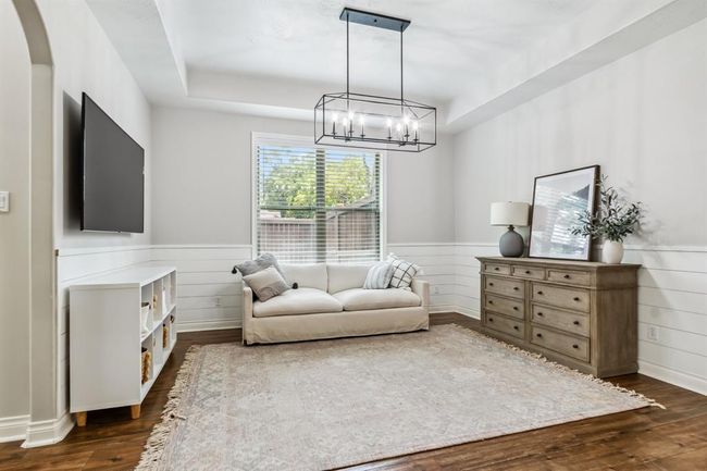 This versatile dining room is currently configured as a comfortable secondary living space, boasting elegant shiplap wainscoting. | Image 8