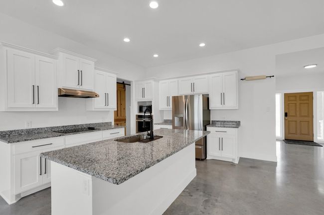 Kitchen featuring stainless steel appliances, under cabinet range hood, a sink, white cabinets, and recessed lighting | Image 17