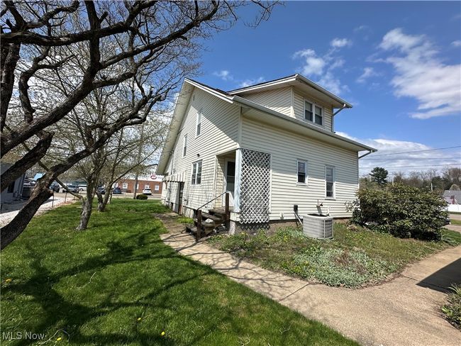 View of side of home featuring a lawn, entry steps, and central air condition unit | Image 21