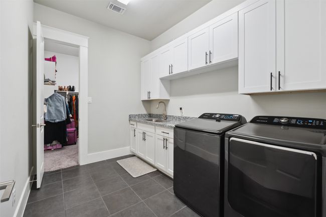 Washroom featuring separate washer and dryer, cabinet space, and dark tile patterned floors | Image 16
