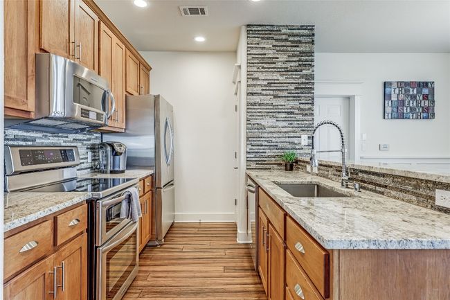 Kitchen with a sink, light wood finished floors, tasteful backsplash, appliances with stainless steel finishes, and visible vents | Image 10