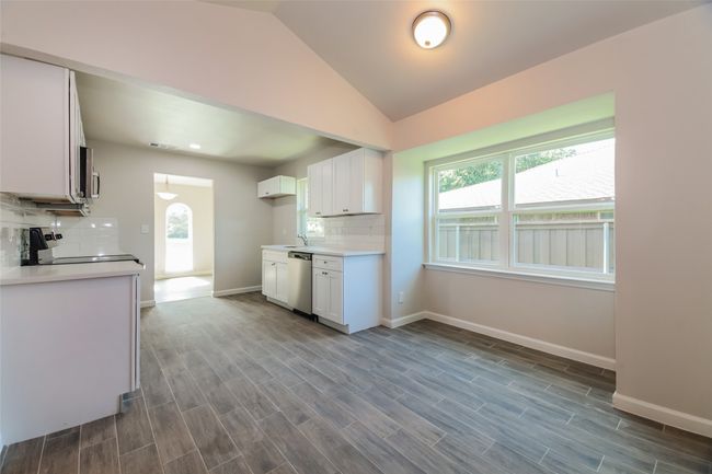 Kitchen with decorative backsplash, vaulted ceiling, white cabinetry, plenty of natural light, and light countertops | Image 11