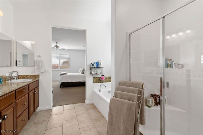 Bathroom with ensuite bathroom, ceiling fan, vanity, tile patterned flooring, and a bath | Image 26