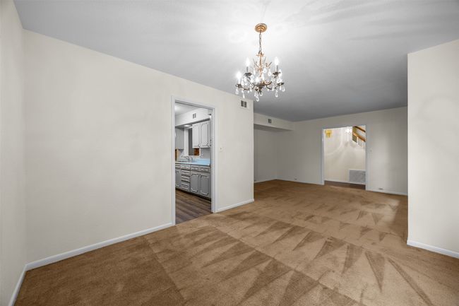 Carpeted empty room with a chandelier, baseboards, and a sink | Image 7