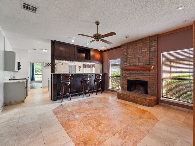 Living room with ceiling fan, a textured ceiling, and a fireplace | Image 13