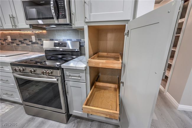 Kitchen featuring stainless steel appliances, light stone countertops, light wood finished floors, and tasteful backsplash | Image 17
