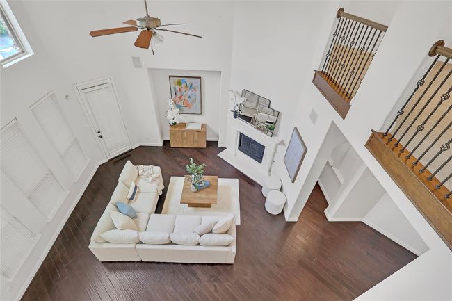 Living room featuring a towering ceiling, wood finished floors, a fireplace, stairs, and ceiling fan | Image 27