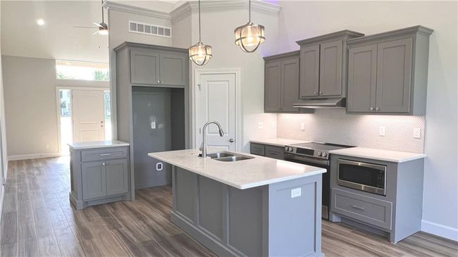 Kitchen with gray cabinets, wood finished floors, and stainless steel appliances | Image 17