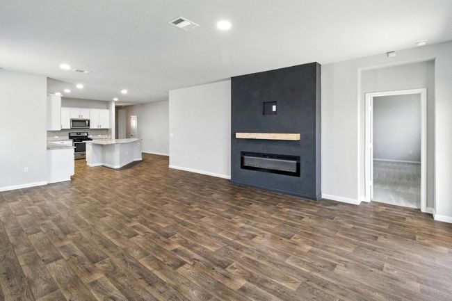 Unfurnished living room featuring dark wood-style floors, recessed lighting, and a large fireplace | Image 8