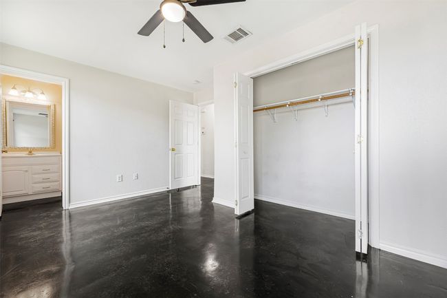 Unfurnished bedroom featuring finished concrete flooring, a closet, connected bathroom, and a ceiling fan | Image 18