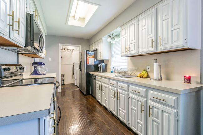 Kitchen featuring stainless steel appliances, white cabinetry, light countertops, and dark wood finished floors | Image 7