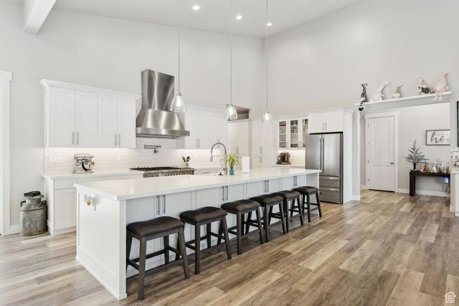 Kitchen featuring a high ceiling, stainless steel appliances, tasteful backsplash, wall chimney range hood, and light countertops | Image 37