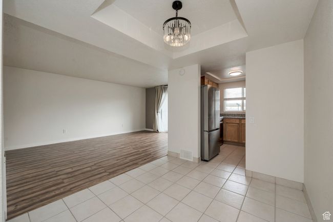 Unfurnished room with a chandelier, a tray ceiling, and light tile patterned floors | Image 5