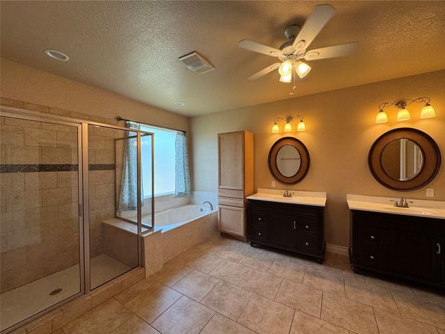 Bathroom with ceiling fan, a garden tub, a stall shower, and a sink | Image 10