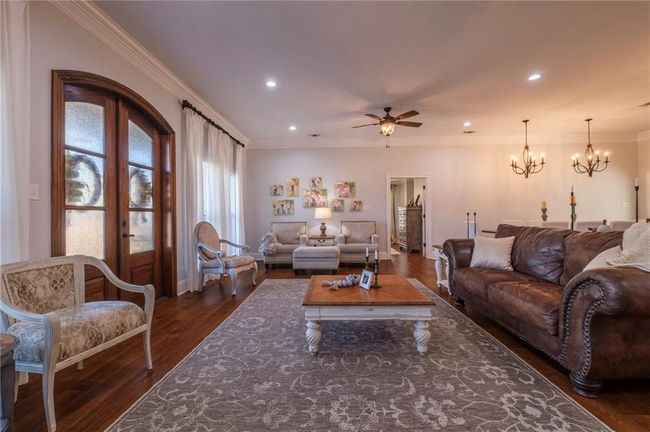 Living room featuring french doors, ceiling fan with notable chandelier, dark hardwood / wood-style floors, and ornamental molding | Image 8